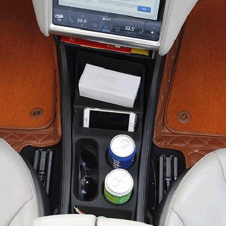 Inside of Tesla Model S showing the the center console organizer insert with a phone, 2 cups and sunglasses on it
